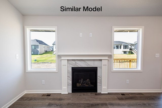 unfurnished living room featuring dark wood-type flooring, a wealth of natural light, and a tile fireplace