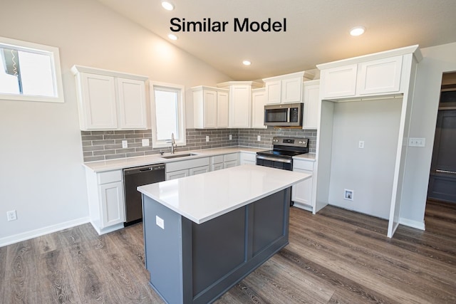 kitchen with stainless steel appliances, backsplash, a kitchen island, white cabinets, and sink