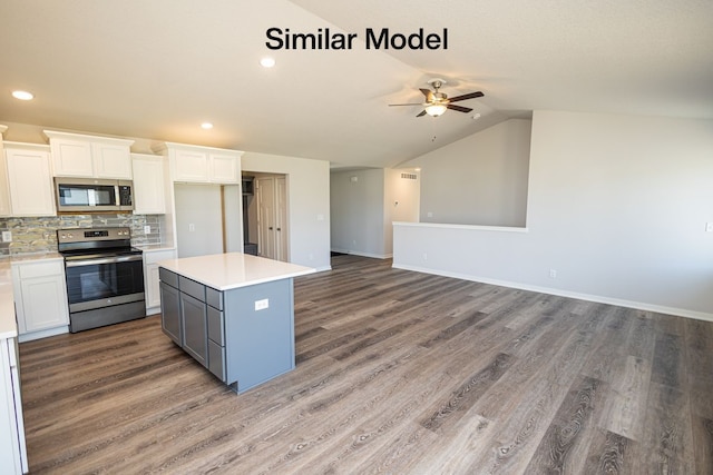 kitchen featuring white cabinets, appliances with stainless steel finishes, a center island, lofted ceiling, and tasteful backsplash