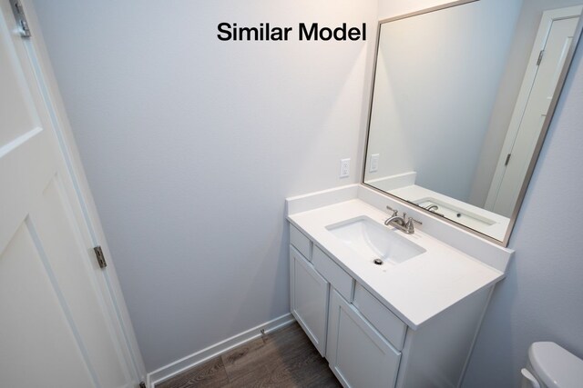 bathroom with toilet, vanity, and hardwood / wood-style flooring