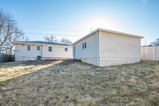 rear view of house featuring central air condition unit and a yard