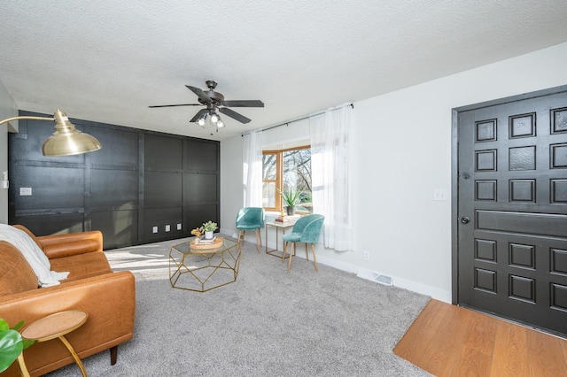 living room with a textured ceiling, ceiling fan, and wood-type flooring