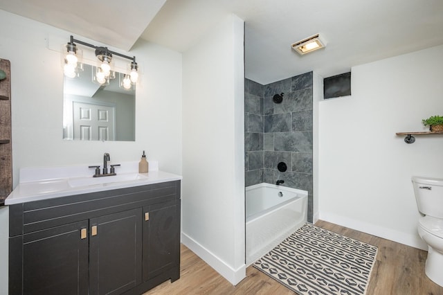 full bathroom featuring toilet, vanity, hardwood / wood-style floors, and tiled shower / bath