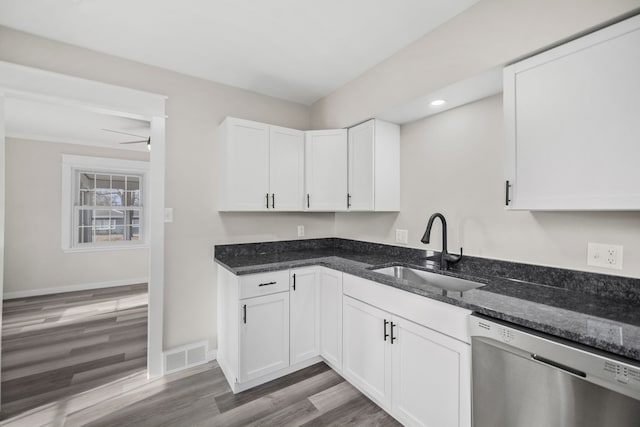 kitchen with dishwasher, white cabinetry, dark stone counters, sink, and light hardwood / wood-style flooring