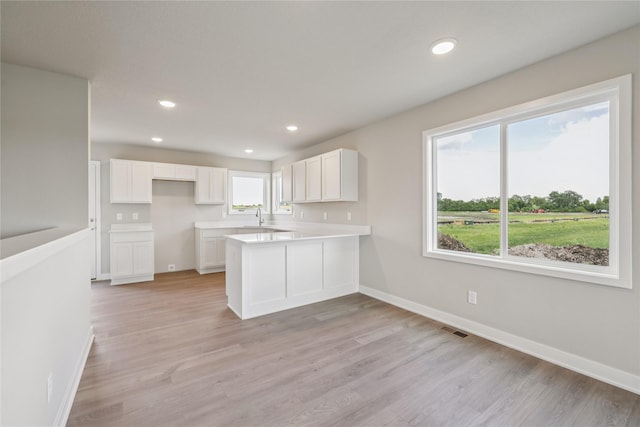 2008 White Oak Ln, Granger, IA 50109 - kitchen featuring light wood-style floors, white cabinets, a peninsula, recessed lighting, and light countertops