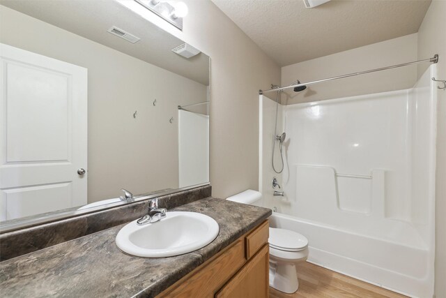 full bathroom with a textured ceiling, bathing tub / shower combination, toilet, wood-type flooring, and vanity