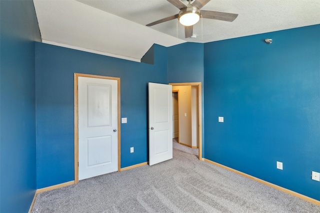 unfurnished bedroom featuring a textured ceiling, ceiling fan, vaulted ceiling, and light colored carpet