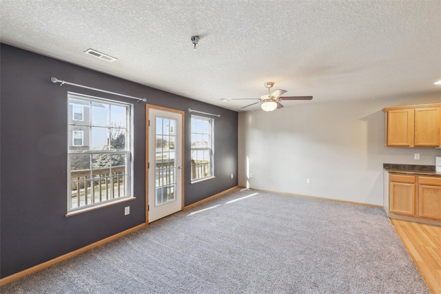 unfurnished living room with a textured ceiling, ceiling fan, and carpet floors