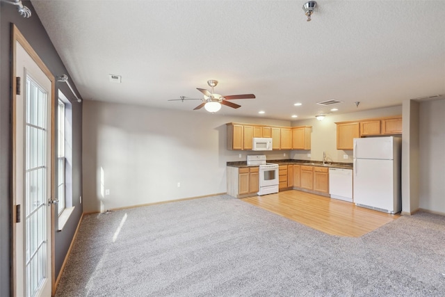 kitchen with sink, light brown cabinets, white appliances, light carpet, and a wealth of natural light