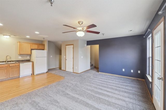 unfurnished living room with sink, ceiling fan, and light colored carpet