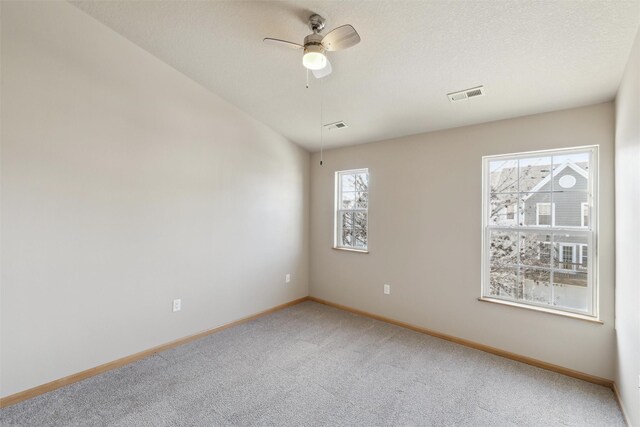 carpeted spare room with ceiling fan and plenty of natural light