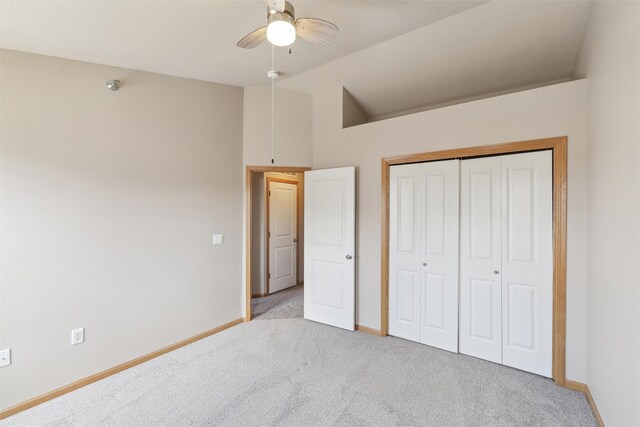 unfurnished bedroom featuring lofted ceiling, ceiling fan, a closet, and light carpet