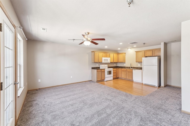 kitchen with light brown cabinetry, white appliances, dark countertops, and light colored carpet