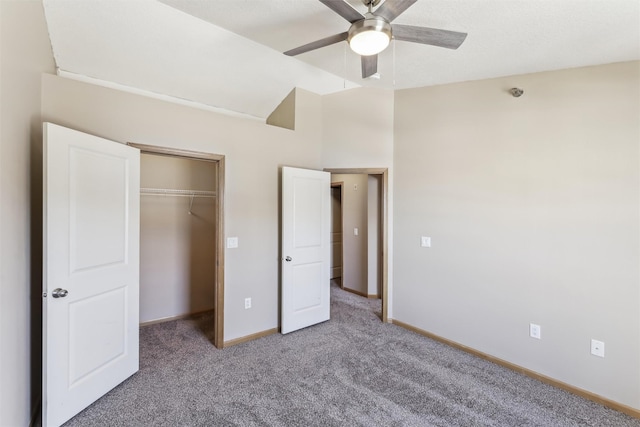 unfurnished bedroom featuring ceiling fan, carpet floors, baseboards, vaulted ceiling, and a closet