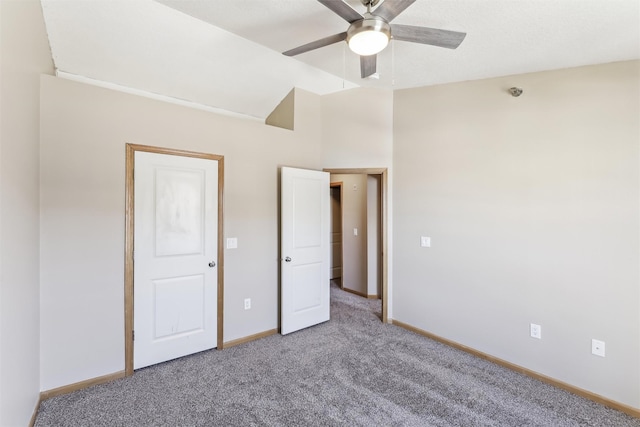 unfurnished bedroom featuring a ceiling fan, lofted ceiling, carpet flooring, and baseboards