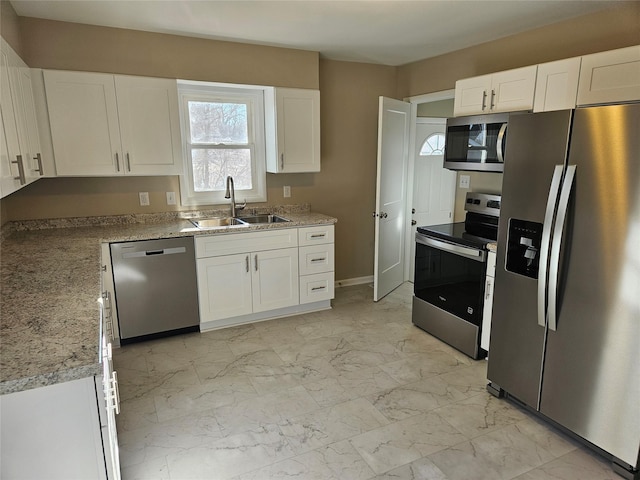 kitchen with sink, white cabinets, light stone countertops, and appliances with stainless steel finishes