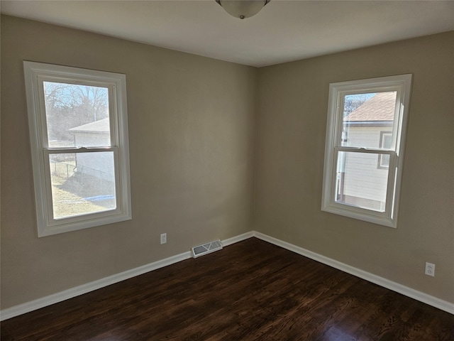 spare room with plenty of natural light and dark wood-type flooring