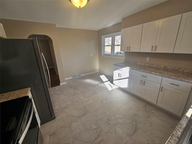 kitchen with stainless steel appliances, white cabinetry, and light stone counters