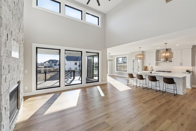 18256 Alderleaf Dr, Clive, IA 50325 - living room featuring a high ceiling, a notable chandelier, a stone fireplace, and a healthy amount of sunlight