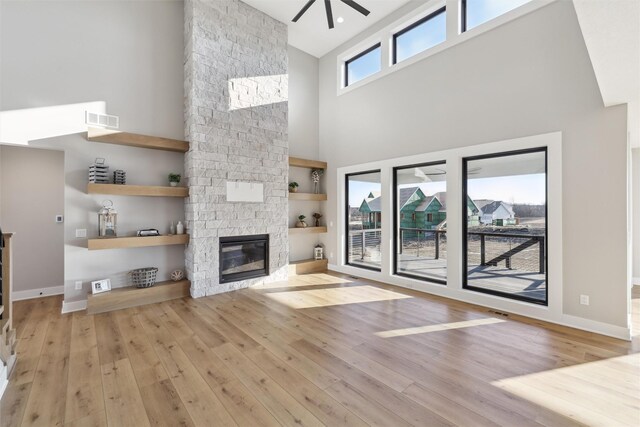 18256 Alderleaf Dr, Clive, IA 50325 - unfurnished living room featuring a ceiling fan, a stone fireplace, visible vents, a towering ceiling, and hardwood / wood-style floors