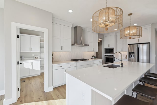 18256 Alderleaf Dr, Clive, IA 50325 - kitchen with wall chimney range hood, a sink, white cabinets, light wood-style floors, and stainless steel appliances