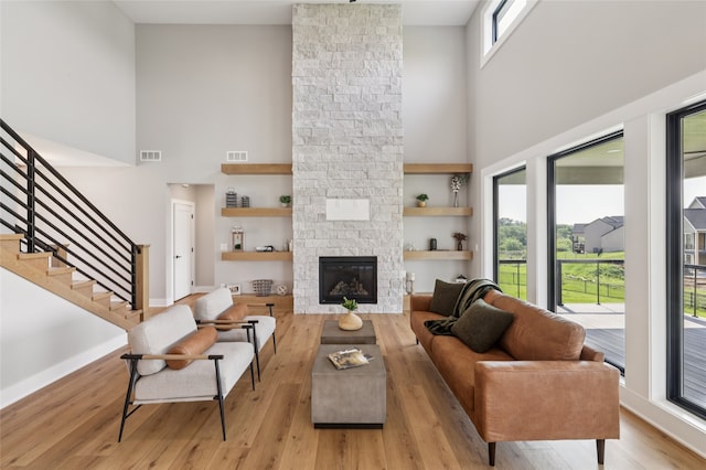 18256 Alderleaf Dr, Clive, IA 50325 - living room with a high ceiling, wood finished floors, a fireplace, built in features, and stairs