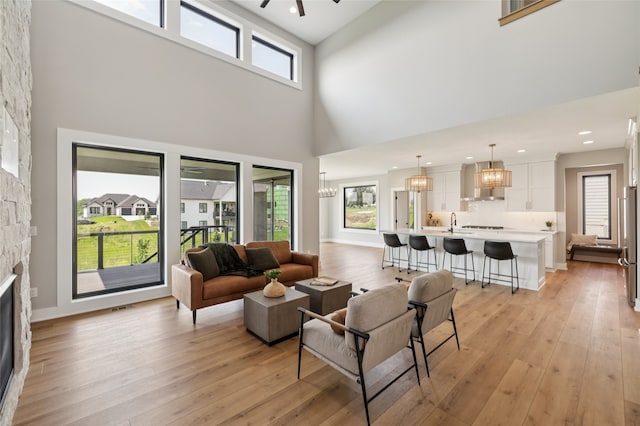 18256 Alderleaf Dr, Clive, IA 50325 - living room featuring a fireplace, a towering ceiling, light wood-style floors, a chandelier, and recessed lighting