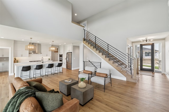 18256 Alderleaf Dr, Clive, IA 50325 - living room featuring a high ceiling, stairway, light wood-type flooring, recessed lighting, and a chandelier