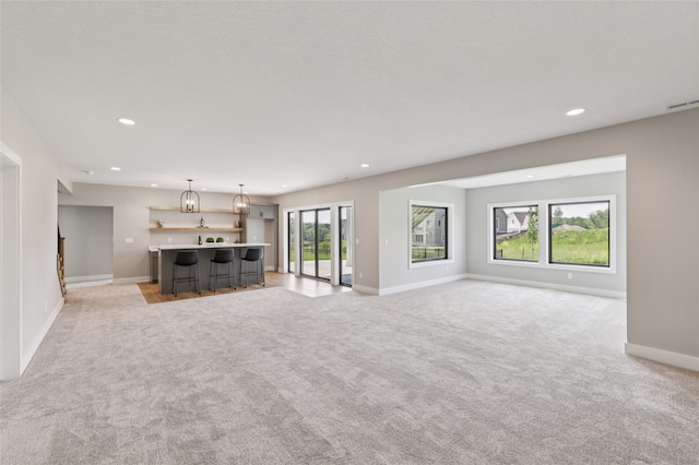 18256 Alderleaf Dr, Clive, IA 50325 - unfurnished living room with light colored carpet, recessed lighting, baseboards, and bar with sink
