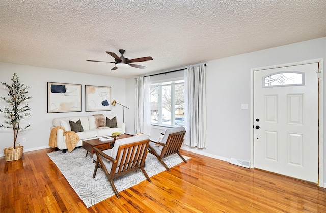 living room with wood-type flooring, a textured ceiling, and ceiling fan