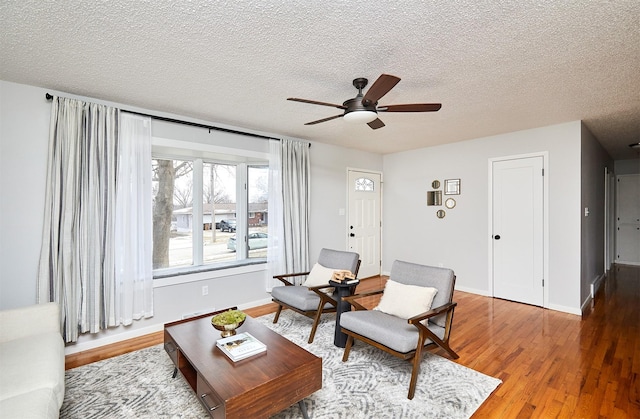 living room with hardwood / wood-style floors, a textured ceiling, and ceiling fan