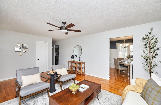 living room featuring ceiling fan with notable chandelier, a textured ceiling, and hardwood / wood-style floors