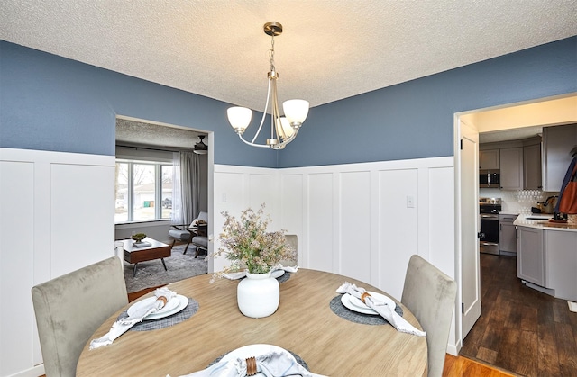 dining room with sink, a textured ceiling, dark hardwood / wood-style flooring, and an inviting chandelier