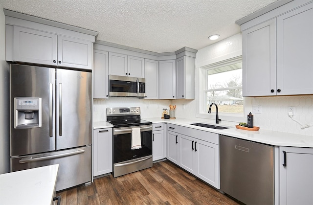 kitchen featuring appliances with stainless steel finishes, dark hardwood / wood-style flooring, gray cabinetry, and sink