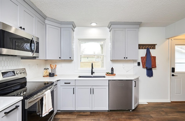 kitchen with gray cabinets, stainless steel appliances, a textured ceiling, dark hardwood / wood-style floors, and sink