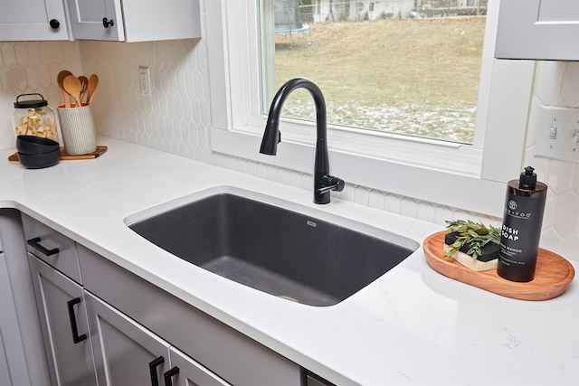 room details featuring sink, backsplash, and gray cabinets