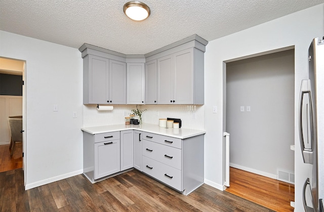 kitchen featuring gray cabinetry, a textured ceiling, dark hardwood / wood-style floors, and stainless steel refrigerator