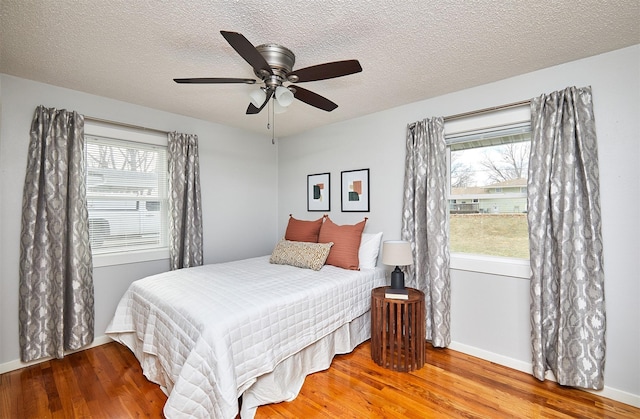 bedroom with wood-type flooring, a textured ceiling, and ceiling fan