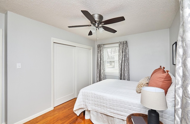 bedroom featuring hardwood / wood-style floors, a closet, ceiling fan, and a textured ceiling