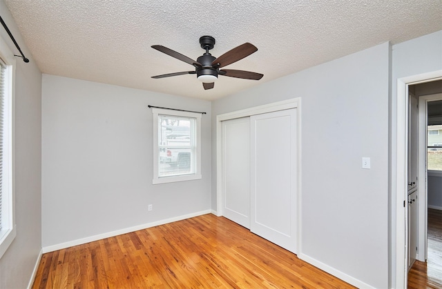 unfurnished bedroom with a textured ceiling, ceiling fan, light hardwood / wood-style flooring, and a closet