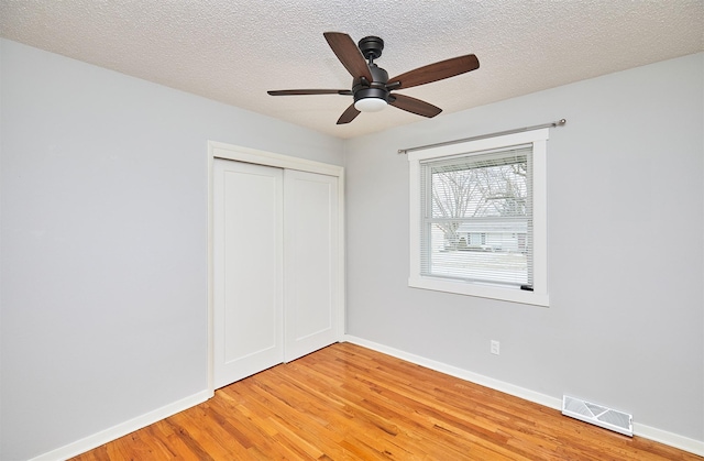 unfurnished bedroom featuring hardwood / wood-style floors, a closet, ceiling fan, and a textured ceiling