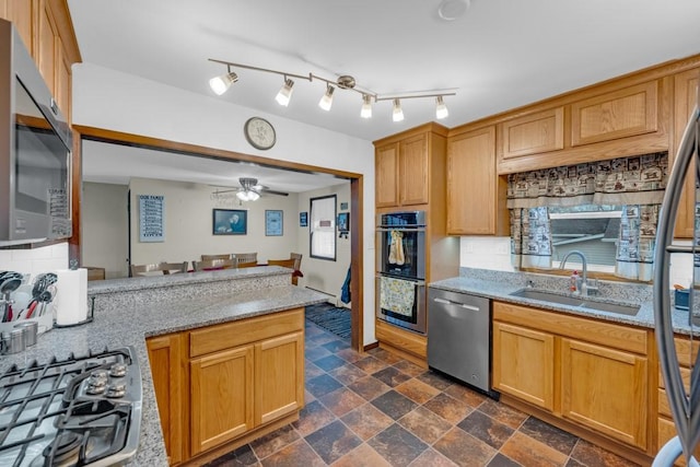 kitchen with appliances with stainless steel finishes, ceiling fan, light stone counters, and sink