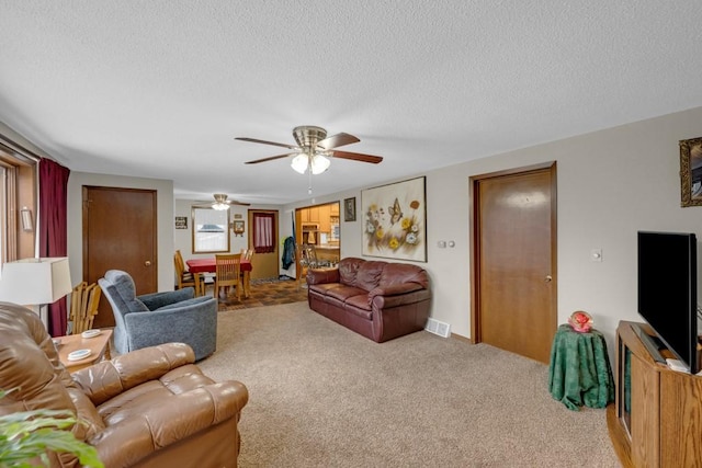 carpeted living room with a textured ceiling and ceiling fan