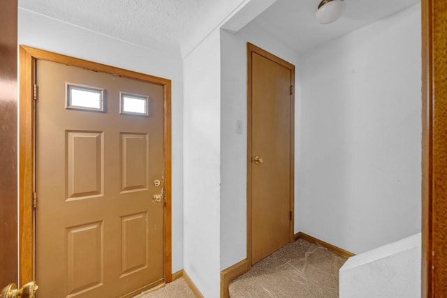 carpeted entryway featuring a textured ceiling