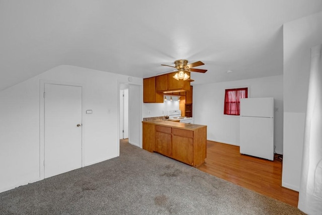 kitchen featuring white appliances, kitchen peninsula, ceiling fan, and carpet flooring