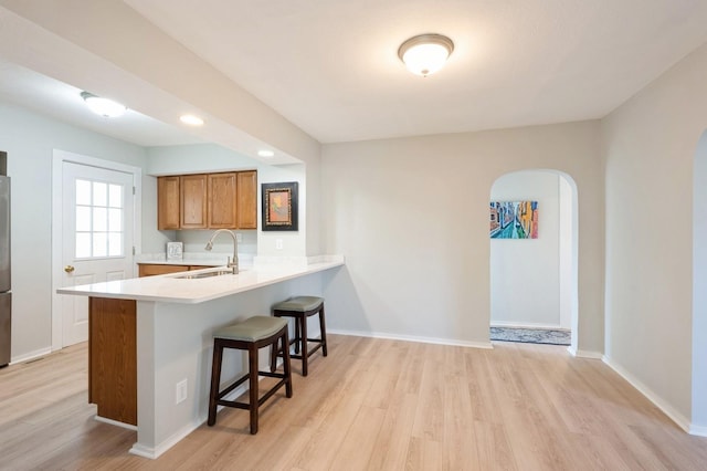 kitchen featuring sink, light wood-type flooring, a breakfast bar, and kitchen peninsula