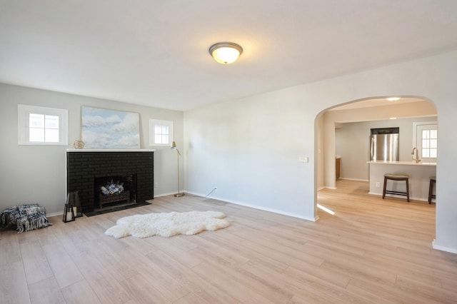 unfurnished living room with a fireplace, light hardwood / wood-style flooring, and a healthy amount of sunlight