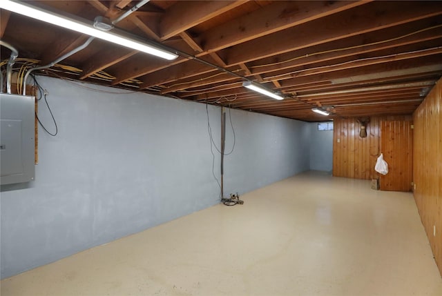 basement featuring electric panel and wood walls