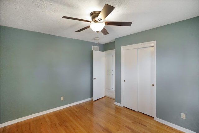 unfurnished bedroom with ceiling fan, light hardwood / wood-style flooring, a closet, and a textured ceiling