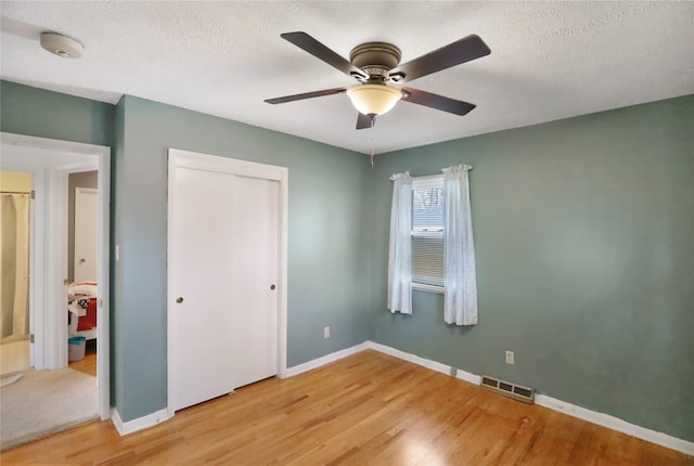 unfurnished bedroom with a textured ceiling, a closet, ceiling fan, and hardwood / wood-style flooring